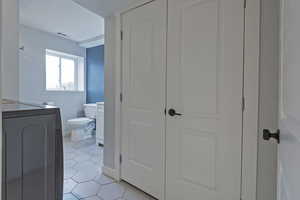 Bathroom with washer / clothes dryer, vanity, tile patterned floors, and toilet