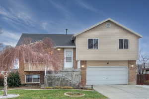 Tri-level home featuring a garage and a front lawn