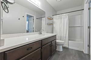 Full bathroom with vanity, shower / tub combo with curtain, and toilet