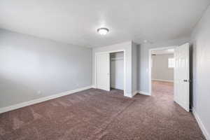 Unfurnished bedroom with carpet, a textured ceiling, and a closet