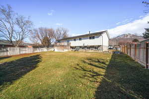 Back of property with a mountain view and a lawn