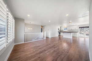 Unfurnished living room featuring sink, dark hardwood / wood-style floors, and a chandelier