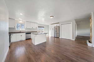 Kitchen featuring a kitchen island, appliances with stainless steel finishes, dark hardwood / wood-style floors, white cabinetry, and sink