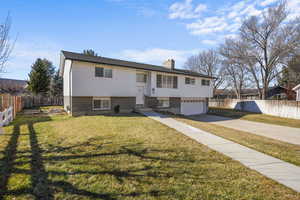 Raised ranch featuring a garage and a front lawn