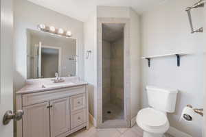 Master bathroom featuring a tile shower, vanity, tile patterned flooring, and toilet