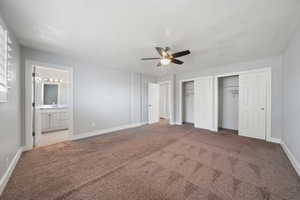 Master bedroom with multiple closets, ensuite bathroom, carpet floors, and a textured ceiling