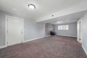 Unfurnished living room featuring a wood stove and carpet