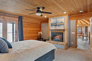 Bedroom with access to exterior, light carpet, wooden ceiling, and wood walls