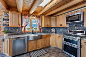 Kitchen with appliances with stainless steel finishes, dark hardwood / wood-style floors, beamed ceiling, sink, and light stone countertops