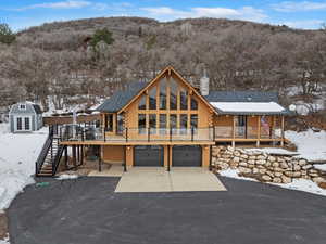 Snow covered property featuring a wooden deck, a garage, and an outbuilding