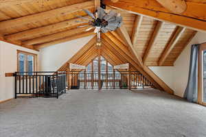 Additional living space with wood ceiling, plenty of natural light, carpet, and vaulted ceiling with beams