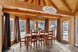 Dining area with a notable chandelier, hardwood / wood-style flooring, lofted ceiling with beams, and wooden ceiling