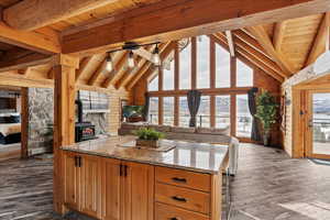 Kitchen featuring a wood stove, dark hardwood / wood-style flooring, light stone countertops, wooden ceiling, and beam ceiling