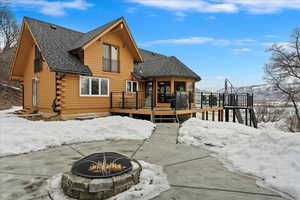 Snow covered rear of property featuring a fire pit and a deck with mountain view