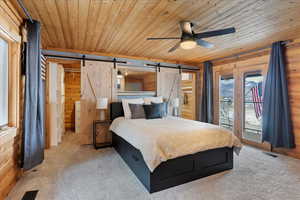 Carpeted bedroom featuring a barn door, access to outside, wood ceiling, and wood walls