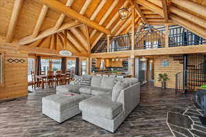 Living room with wood ceiling, wooden walls, dark hardwood / wood-style floors, lofted ceiling with beams, and a chandelier