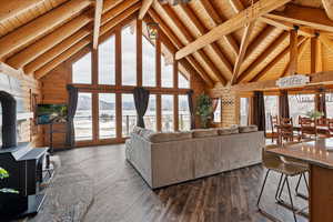 Living room with dark wood-type flooring, beamed ceiling, wood ceiling, and a wood stove