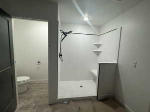 Bathroom featuring toilet, concrete floors, and a shower