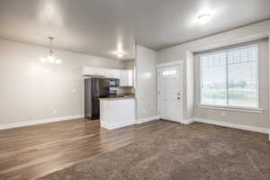 Kitchen featuring pendant lighting, an inviting chandelier, black appliances, a textured ceiling, and white cabinets