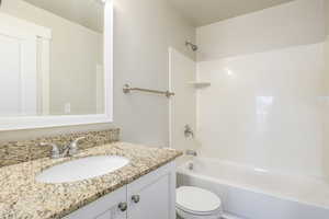 Full bathroom with washtub / shower combination, vanity, and toilet