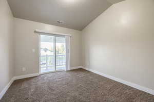 Carpeted empty room featuring lofted ceiling and a textured ceiling