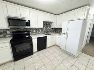 Kitchen with white cabinets, sink, and black appliances