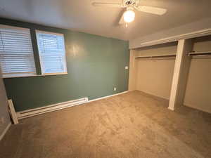 Unfurnished bedroom with ceiling fan, light colored carpet, a closet, and a baseboard heating unit