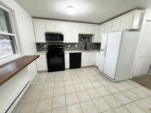 Kitchen featuring white cabinetry, a baseboard heating unit, black appliances, and sink