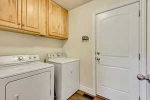 Washroom with cabinets, hardwood / wood-style flooring, and independent washer and dryer