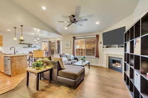 Living room with lofted ceiling, sink, ceiling fan, and light hardwood / wood-style flooring