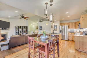 Dining area with vaulted ceiling, sink, a tiled fireplace, and light hardwood / wood-style floors