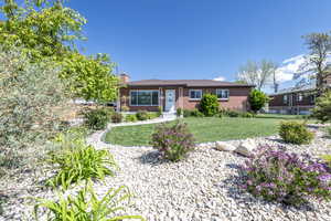 Ranch-style house with brick siding, fence, a chimney, and a front lawn