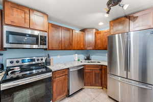 Kitchen with light stone counters, sink, light tile patterned floors, and stainless steel appliances / basement kitchen