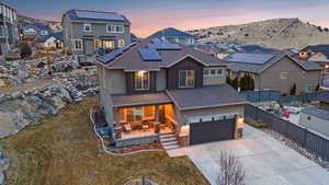 View of front of property featuring a garage, a mountain view, a yard, and solar panels