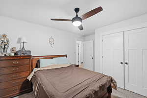 Carpeted bedroom featuring ceiling fan and a closet