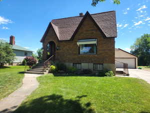 View of front of home with a garage, an outdoor structure, and a front yard