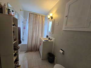 Full bathroom with toilet, vanity, tile patterned floors, and shower / bath combo with shower curtain