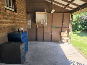 Exterior space with concrete flooring, vaulted ceiling, and brick wall