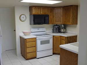 Kitchen with white electric stove and light tile