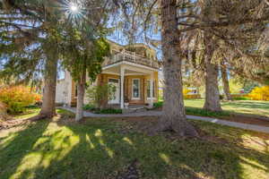 View of front of property with a front yard and a balcony