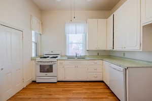 Kitchen featuring white cabinetry, white appliances, and sink