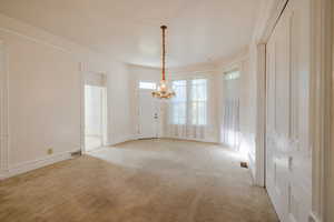 Carpeted spare room with an inviting chandelier