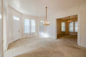 Interior space with light colored carpet and an inviting chandelier