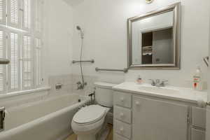 Bathroom featuring vanity, toilet, a washtub, and a wealth of natural light