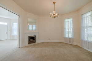 Formal living room with an inviting chandelier, carpet floors, and a healthy amount of sunlight