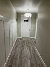 Doorway featuring dark hardwood / wood-style flooring, a textured ceiling, and an inviting chandelier