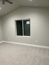 Carpeted empty room featuring ceiling fan and lofted ceiling