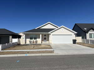 View of front of home featuring a garage, concrete driveway, stone siding, and fence