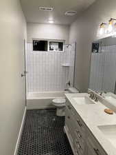 Full bathroom featuring vanity, tiled shower / bath combo, and toilet