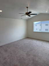 Carpeted spare room with vaulted ceiling, a textured ceiling, and ceiling fan